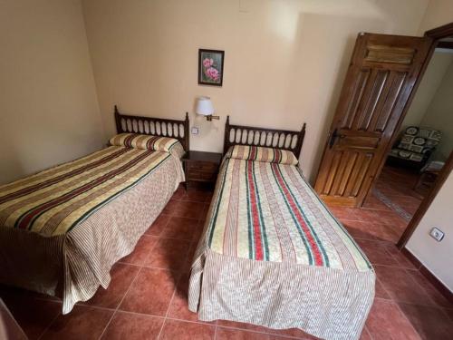 a room with two beds in a room with a door at Apartamentos Turísticos La Posada in Oropesa