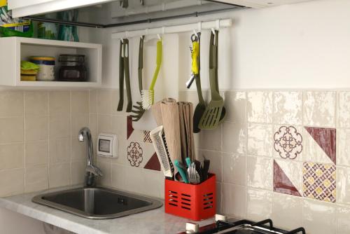 a kitchen counter with utensils hanging on the wall at Central Apartment with Panoramic Terrace in Catania