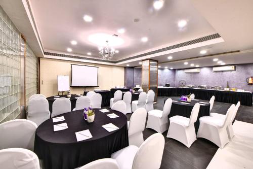 a conference room with white chairs and tables and a screen at The Fern Residency, Subhash Bridge, Ahmedabad in Ahmedabad