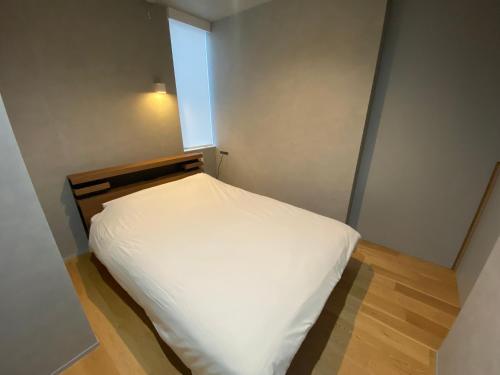 a small bedroom with a white bed with a window at Villa Monica EAST in Nagoya