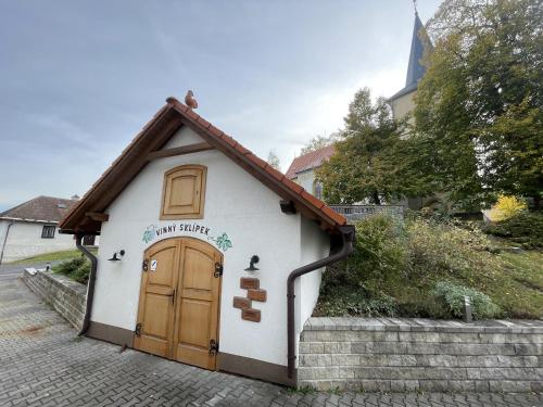 a small white building with a wooden door at Penzion a restaurace U Nováků in Bítovany