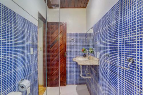 uma casa de banho em azulejos azuis com um lavatório e um chuveiro em Pousada casa zaza em Itacaré
