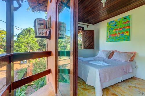 a bedroom with a bed and a large window at Pousada casa zaza in Itacaré