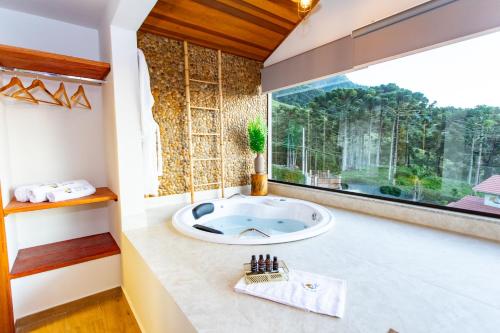 a bathroom with a tub and a large window at Chalés Quinta da Boa Vista in São Bento do Sapucaí