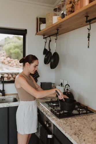 a woman in a kitchen preparing food in a pan at Spionkop Eco Cabin in Reddersburg
