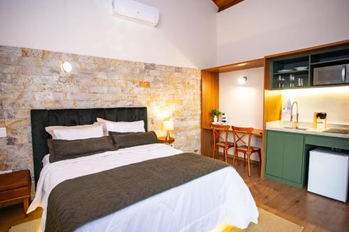 a bedroom with a large bed and a kitchen at Chalés Quinta da Boa Vista in São Bento do Sapucaí