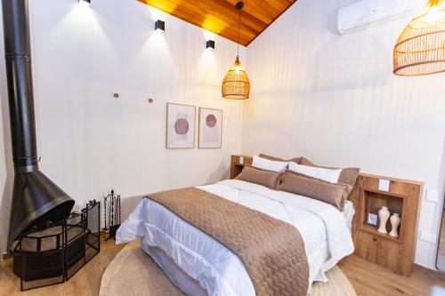 um quarto com uma cama com paredes brancas e uma lareira em Chalés Quinta da Boa Vista em São Bento do Sapucaí