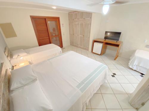 a white bedroom with two beds and a desk at Pousada Montemar in Ilhabela