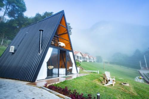 ein kleines Haus mit schwarzem Dach auf einem Feld in der Unterkunft Chalés Quinta da Boa Vista in São Bento do Sapucaí