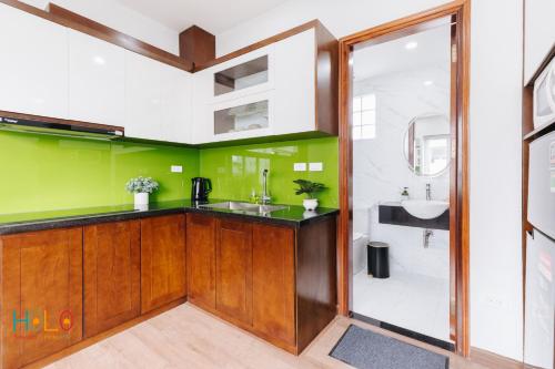 a bathroom with green walls and a counter with a sink at HoLo Central Hanoi - Serviced HomeStay in Hanoi