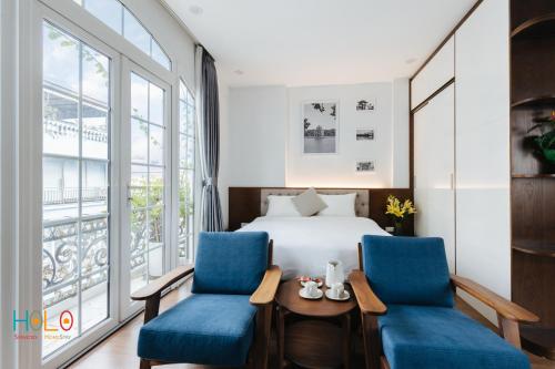 a hotel room with a bed and two blue chairs at HoLo Central Hanoi - Serviced HomeStay in Hanoi