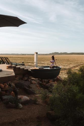 a woman sitting on a boat on the beach at Spionkop Eco Cabin in Reddersburg