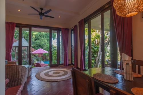 a living room with a dining table and glass doors at Villa Awang - awang in Ubud