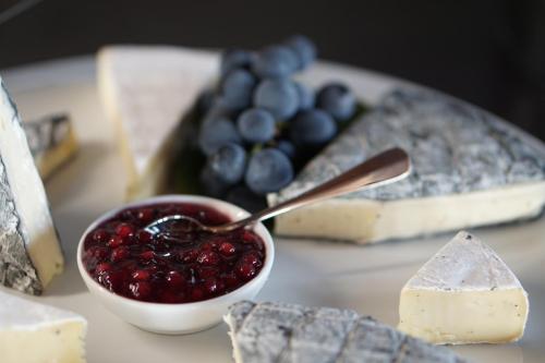 a plate of cheese and a bowl of jam with cheese and grapes at Mahorko Wein Wellness Wasserbüffel in Glanz an der Weinstraße 