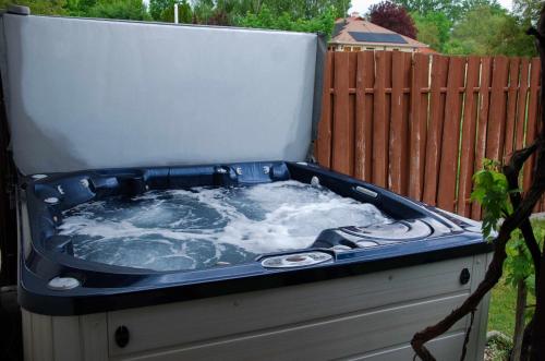 a hot tub sitting in a yard next to a fence at Szelidi Apartmanok in Dunapataj