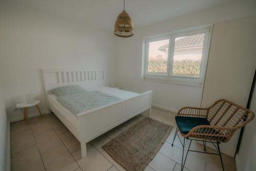 a white bedroom with a bed and a chair at Gästehaus zum Schloßpark in Schwerin