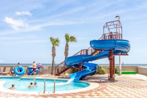 a water slide at a resort with people in a pool at The Bluebird OBA at Phoenix West II in Orange Beach