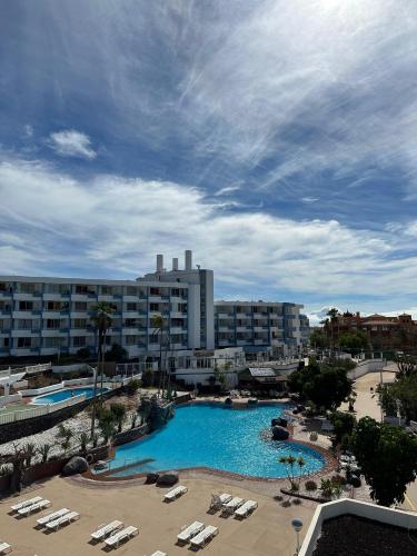 a large swimming pool with lounge chairs and a hotel at Golf del Sur Tenerife - Casa Barrera verde green park la corbeta in San Miguel de Abona