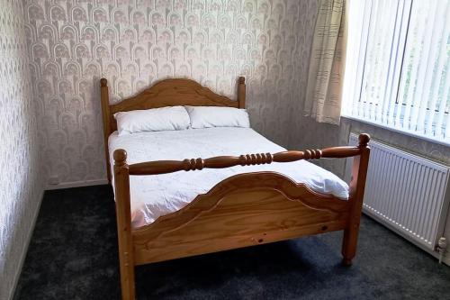 a wooden bed with white sheets and pillows in a bedroom at Relax near Wollaton Park in Nottingham