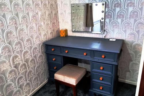 a blue dresser with a stool and a mirror at Relax near Wollaton Park in Nottingham