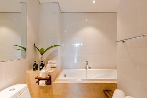 a white bathroom with a tub and a toilet at De Old Sport - Vesta Collections in Ho Chi Minh City