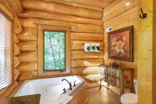 a log cabin bathroom with a tub and a window at Big Bear Ridge Lodge - Breathtaking mountain views and private forest scenes in amazing large log cabin in Gatlinburg