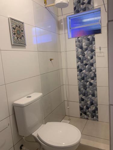 um banheiro com um vaso sanitário branco e um chuveiro em Toca da Suzara Suíte 1 até 4 pessoas Piscina Rio e Mar num só lugar em Florianópolis