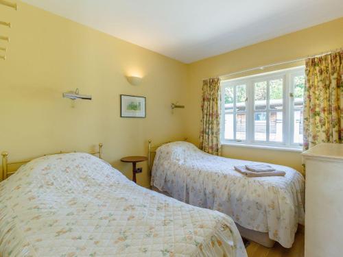 a bedroom with two beds and a window at Curlew Cottage in Hexham
