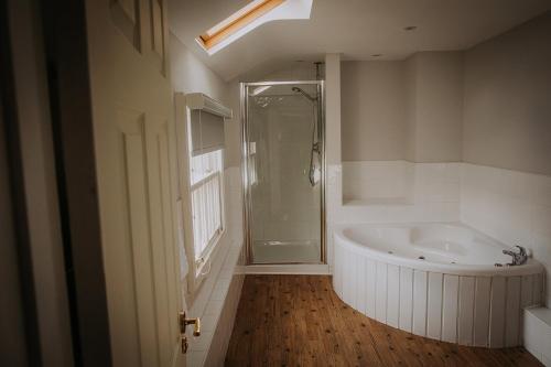 a bathroom with a shower and a tub and a sink at The Lake Isle Restaurant with rooms in Uppingham