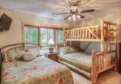 a bedroom with two bunk beds and a ceiling fan at Big Bear Ridge Lodge - Breathtaking mountain views and private forest scenes in amazing large log cabin in Gatlinburg