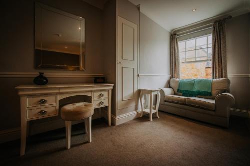 a living room with a couch and a dresser and a window at The Lake Isle Restaurant with rooms in Uppingham