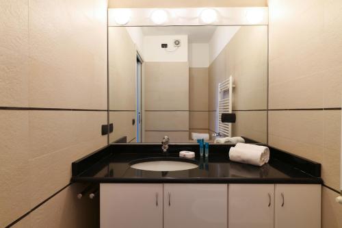 La salle de bains est pourvue d'un lavabo et d'un miroir. dans l'établissement Contempora Apartments - trilocale Largo Zanuso, à Milan