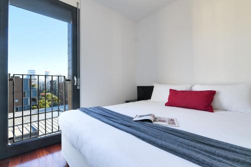 Contempora Apartments - trilocale Largo Zanuso في ميلانو: غرفة نوم بسرير ومخدة حمراء ونافذة