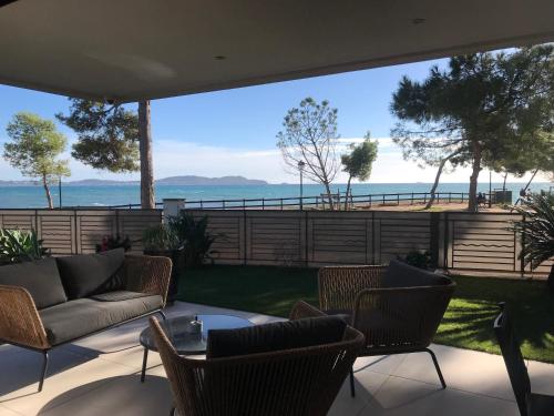 un patio avec des chaises, un canapé et une table dans l'établissement Bord de mer aux Pins Penchés, à Carqueiranne