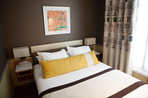 a bedroom with a bed with a yellow pillow and a window at Hotel La Manufacture in Paris