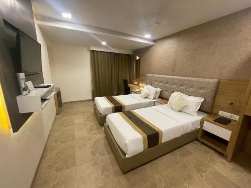 a hotel room with two beds and a television at Hotel Grace Galaxy in Mumbai