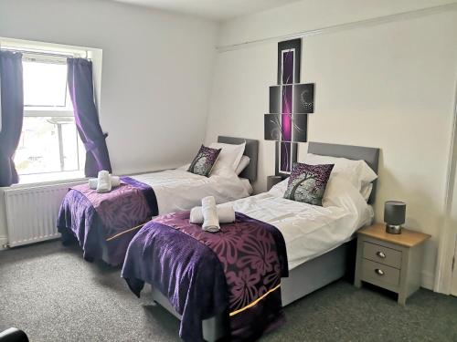 a bedroom with two beds with purple and white sheets at Nick's Place in Plymouth
