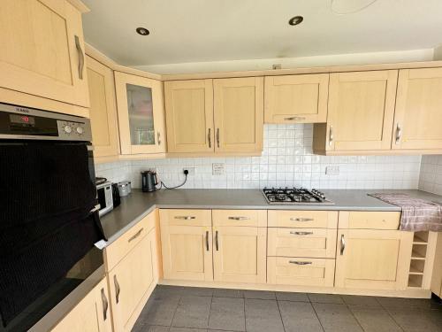 a kitchen with wooden cabinets and a stove top oven at Basingstoke Guesthouse in Basingstoke