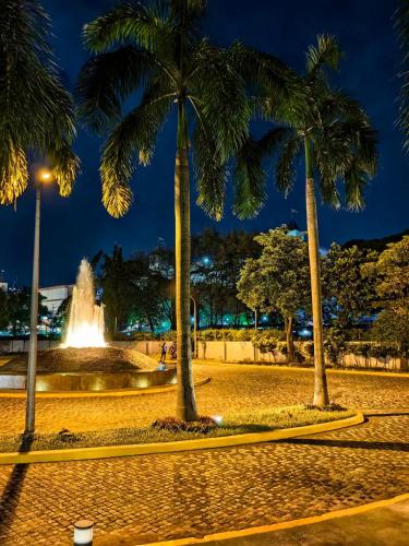 a park with palm trees and a fountain at night at Cozy Oasis, Mountain + Skyline View, Free Pool in Manila