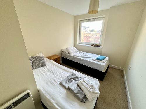 Duas camas num pequeno quarto com uma janela em Elvetham Nest Guesthouse, Basingstoke em Basingstoke