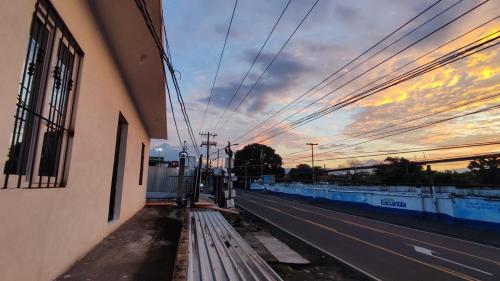 an empty street with a building and a sunset at Apartamento Pradera's in Escuintla