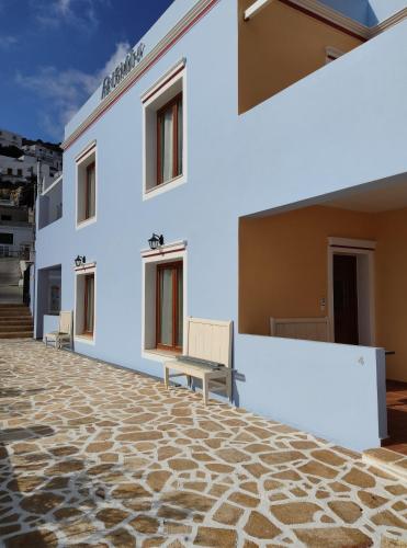 un edificio bianco con pavimento in pietra e panche di Anemi Leros Apartments 4 a Panteli