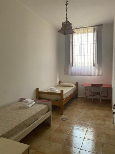 Zimmer mit 2 Betten, einem Tisch und einem Fenster in der Unterkunft Casa vacanza “O Bagghiu” in Bagheria