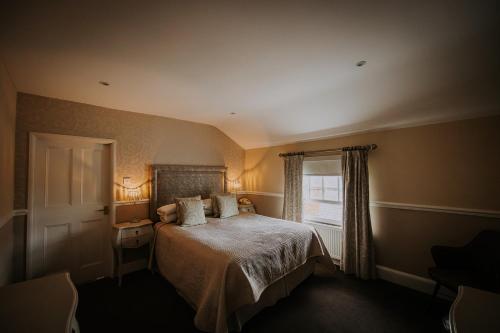 a bedroom with a bed and a window at The Lake Isle Restaurant with rooms in Uppingham