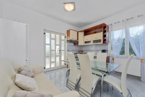 a living room with a glass table and white chairs at Villa Almas - Heated Pool, Sauna, Gym and Tennis Court in Neorić