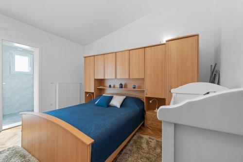 a bedroom with a blue bed and wooden cabinets at Villa Almas - Heated Pool, Sauna, Gym and Tennis Court in Neorić