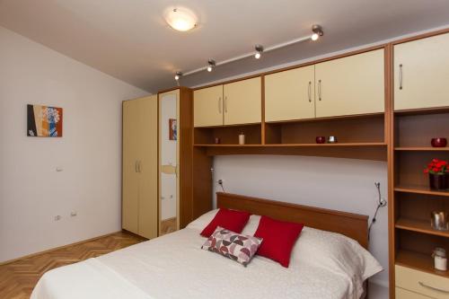 a bedroom with a bed with wooden cabinets and red pillows at Villa Almas - Heated Pool, Sauna, Gym and Tennis Court in Neorić