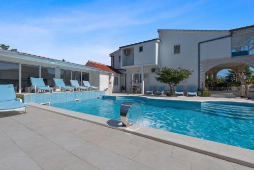 a swimming pool with chairs next to a building at Villa Almas - Heated Pool, Sauna, Gym and Tennis Court in Neorić