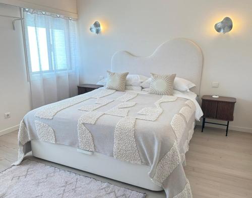 a white bedroom with a large white bed with white sheets and pillows at Groovy Caparica Gem with Large Sunny Terrace in Costa da Caparica