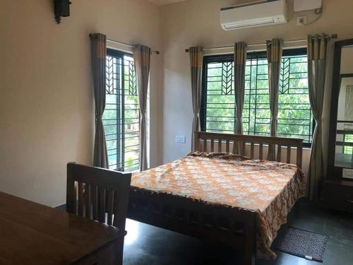 um quarto com uma cama, uma mesa e janelas em Elim-A Sedate Nest em Santiniketan